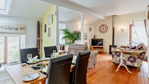A living room with a dining area, a sofa, a TV, and a fireplace. - 2 Bed in Brixham (oc-bx083) (Brixham)