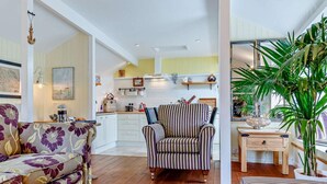 A living room with a sofa, a striped armchair, and a dining area with a table and chairs. - 2 Bed in Brixham (oc-bx083) (Brixham)