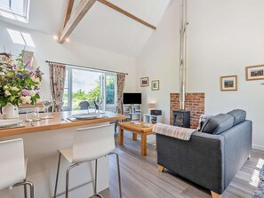 Una sala de estar moderna con chimenea, un comedor con mesa y sillas, y un amplio ventanal con cortinas.