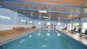 Ein Hallenbad mit blau gefliestem Boden, Holzboden und einer blauen Metallträgerkonstruktion.