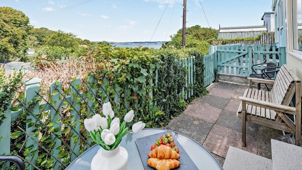 Eine Terrasse mit Tisch, einem Blumenstrauß und einem Teller Essen.