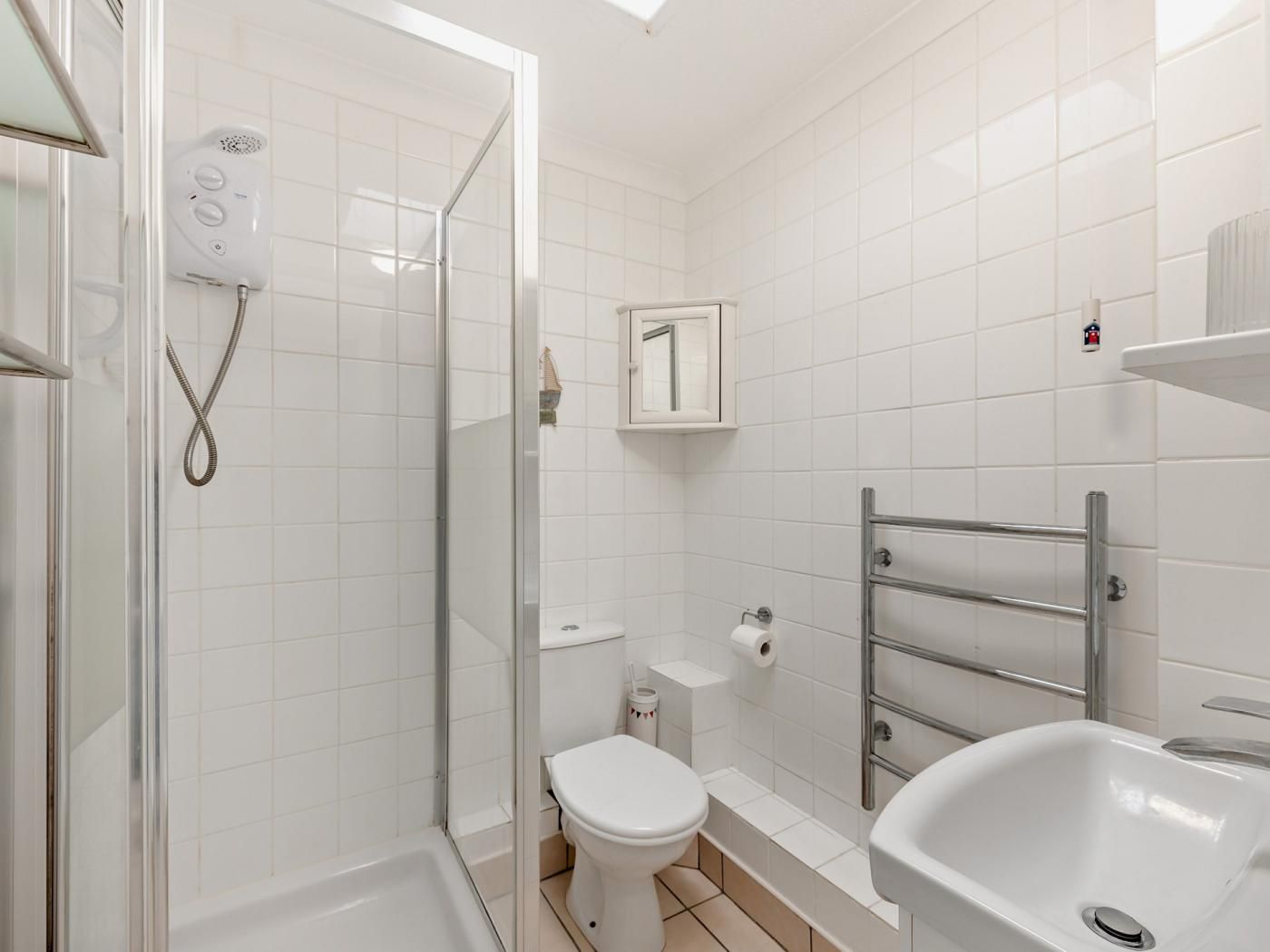 Une salle de bain avec une douche à parois de verre, des toilettes blanches, un lavabo et un porte-serviettes.