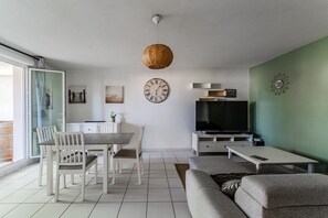 Ett modernt vardagsrum med en matplats, en tv och en stor väggklocka.