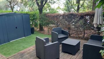 An outdoor patio area with wicker furniture, a wooden deck, and a blue shed.