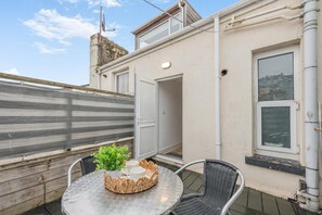 A balcony with a round table, two chairs, a potted plant, and a view of the cityscape. - 2 Bed in Brixham (oc-54679) (Brixham)