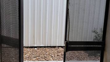 A metal gate with a mesh design, an EXIT sign above it, and a concrete floor with a yellow line.