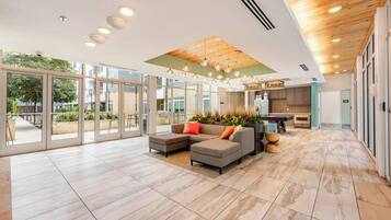 A spacious living area with a sectional sofa, a kitchen in the background, and large windows.