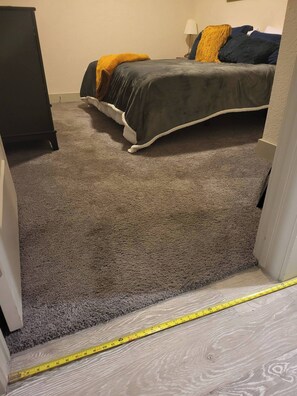 Habitación con alfombra, cama, mesita de noche y lámpara.