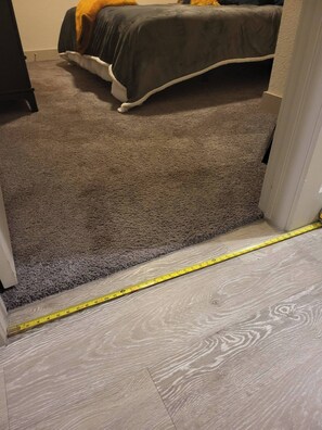 A carpeted hallway leading to a bedroom with a bed and a nightstand. - Chic Riverwalk Facing Condo Pool View Free Parking Pets Welcome (San Antonio)