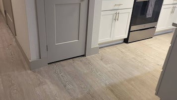 A kitchen with white cabinets, a microwave, an oven, and a coffee maker.