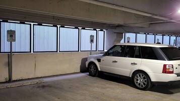 Een parkeergarage met een witte SUV geparkeerd in een gereserveerde plek voor mindervaliden.