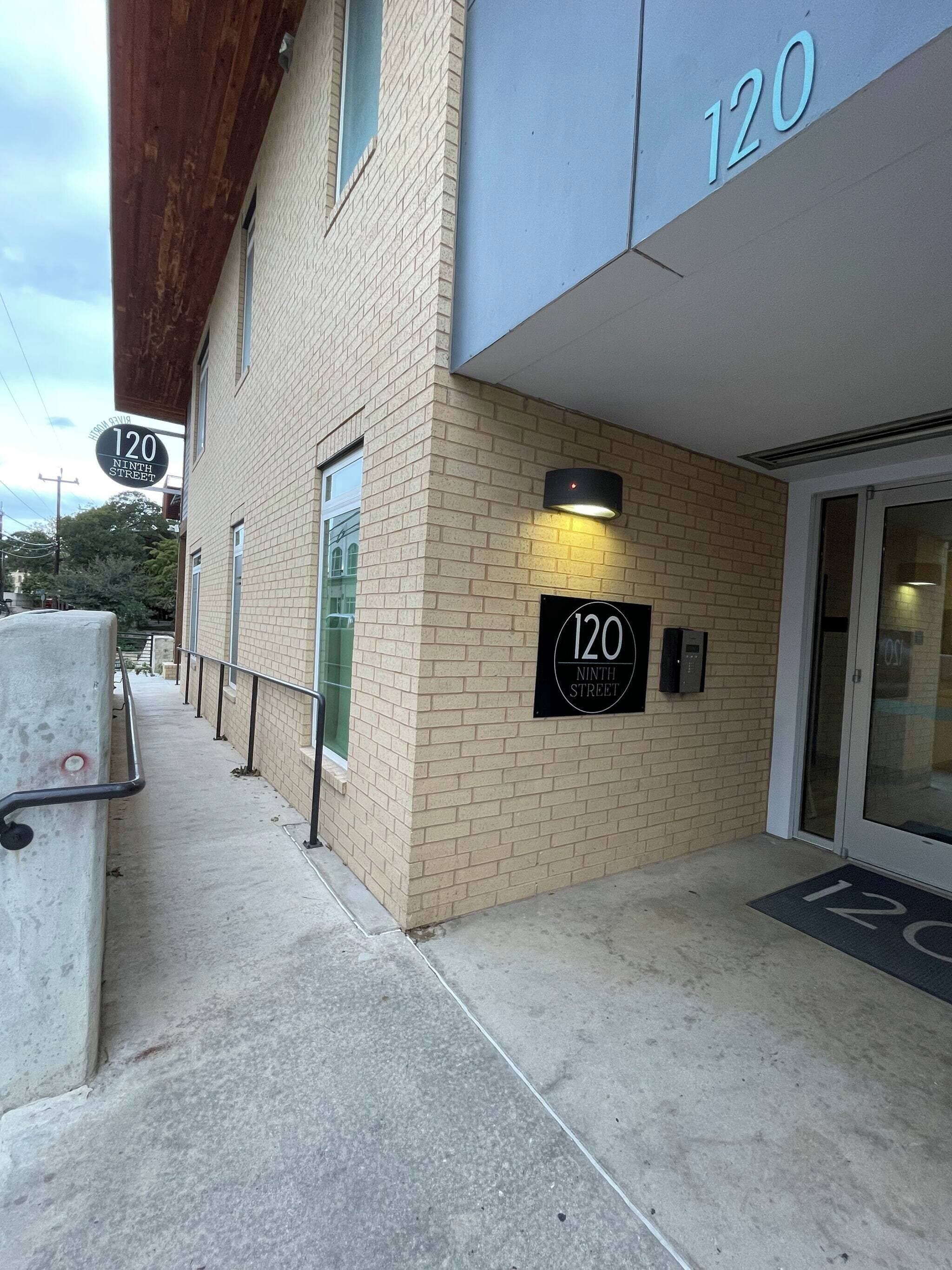 A building with a brick facade, a sign indicating '120 Ninth Street,' and a door with a glass panel.