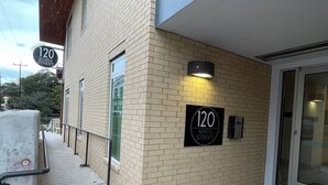 Um edifício com fachada de tijolos, uma placa indicando '120 Ninth Street' e uma porta com painel de vidro.