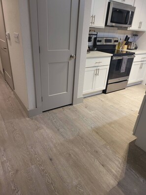 A kitchen with white cabinets, a microwave, a stove, and a sink.
