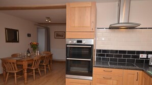 A kitchen with wooden cabinets, a double oven, and a tiled backsplash. - 3 Bed in Wells (oc-55232) (Green Ore)