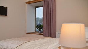 A bedroom with a bed, a window with curtains, a bedside lamp, and a radiator. - 3 Bed in Wells (oc-55232) (Green Ore)