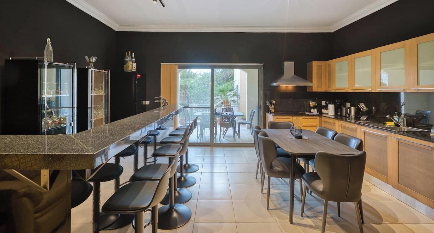 Una cocina moderna con barra, comedor y ventanas amplias.