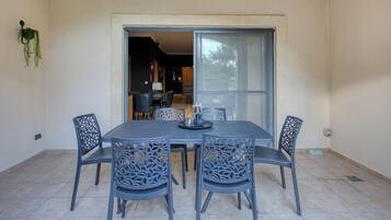 Comedor con mesa y sillas, una ventana y una puerta que da a otra habitación.