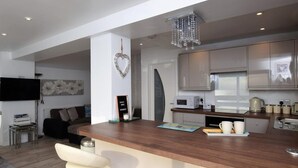 A modern kitchen with a bar area, stainless steel appliances, and a chandelier. - 2 Bed in Pevensey (oc-55355) (Pevensey Bay)