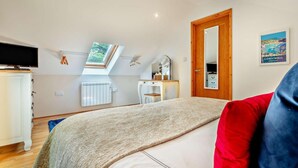 A bedroom with a bed, a desk, a mirror, a radiator, a TV, and a skylight. - 1 Bed in Newquay (oc-55333) (Trebudannon)