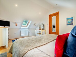 A bedroom with a bed, a desk, a mirror, a radiator, a TV, and a skylight. - 1 Bed in Newquay (oc-55333) (Trebudannon)