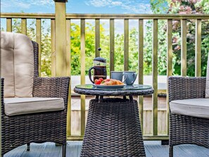 A balcony with wicker chairs and a table, a coffee pot, and a plate of strawberries. - 1 Bed in Newquay (oc-55333) (Trebudannon)