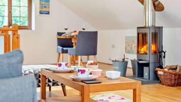 A cozy living room with a wooden table set for tea, a fireplace, and a dining area with chairs.