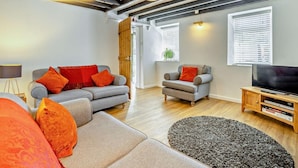 A modern living room with a grey sofa, armchair, and a TV stand. - 3 Bed in Pwllheli (oc-55571) (Nefyn)
