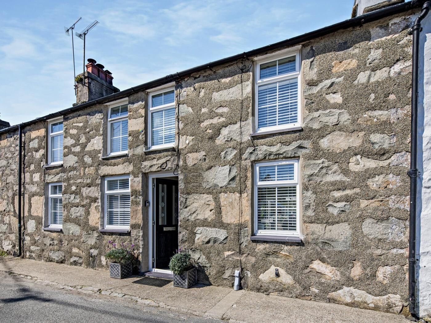 A stone building with multiple windows and a door, featuring a traditional architectural style.