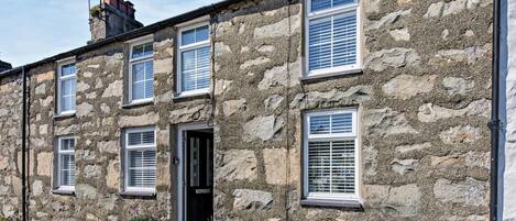 A stone building with multiple windows and a door, featuring a traditional architectural style.