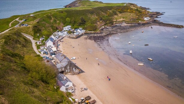 A coastal village with a sandy beach, a lighthouse, and a small harbor. - 3 Bed in Pwllheli (oc-55571) (Nefyn)