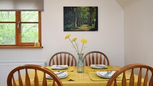 A dining area with a table set for four, a painting of a forest, and a window with a view of trees. - 2 Bed in Canterbury (oc-55811) (Waltham)