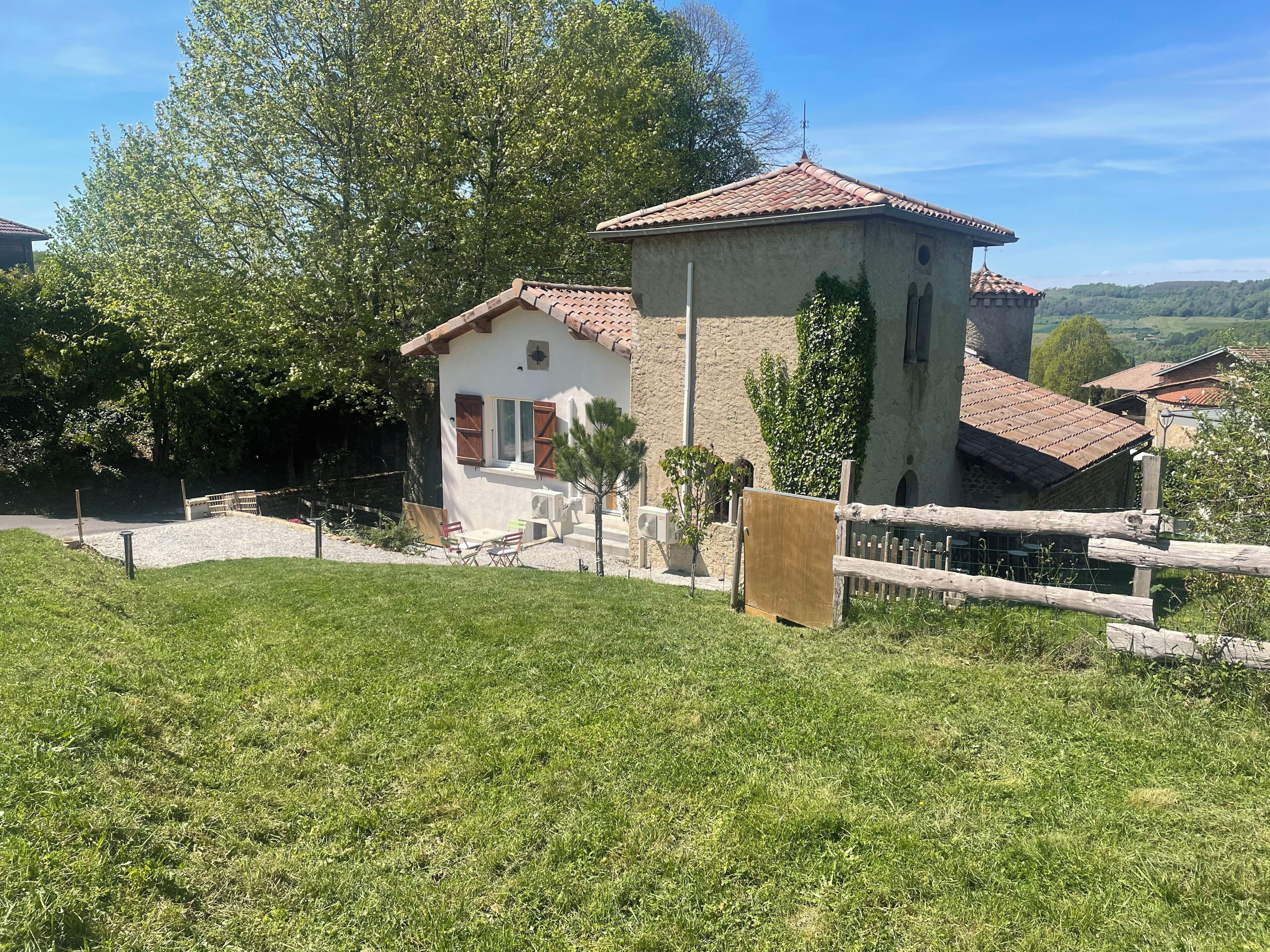 Ein rustikales Haus mit Ziegeldach, einem kleinen Turm und einem Holzzaun.