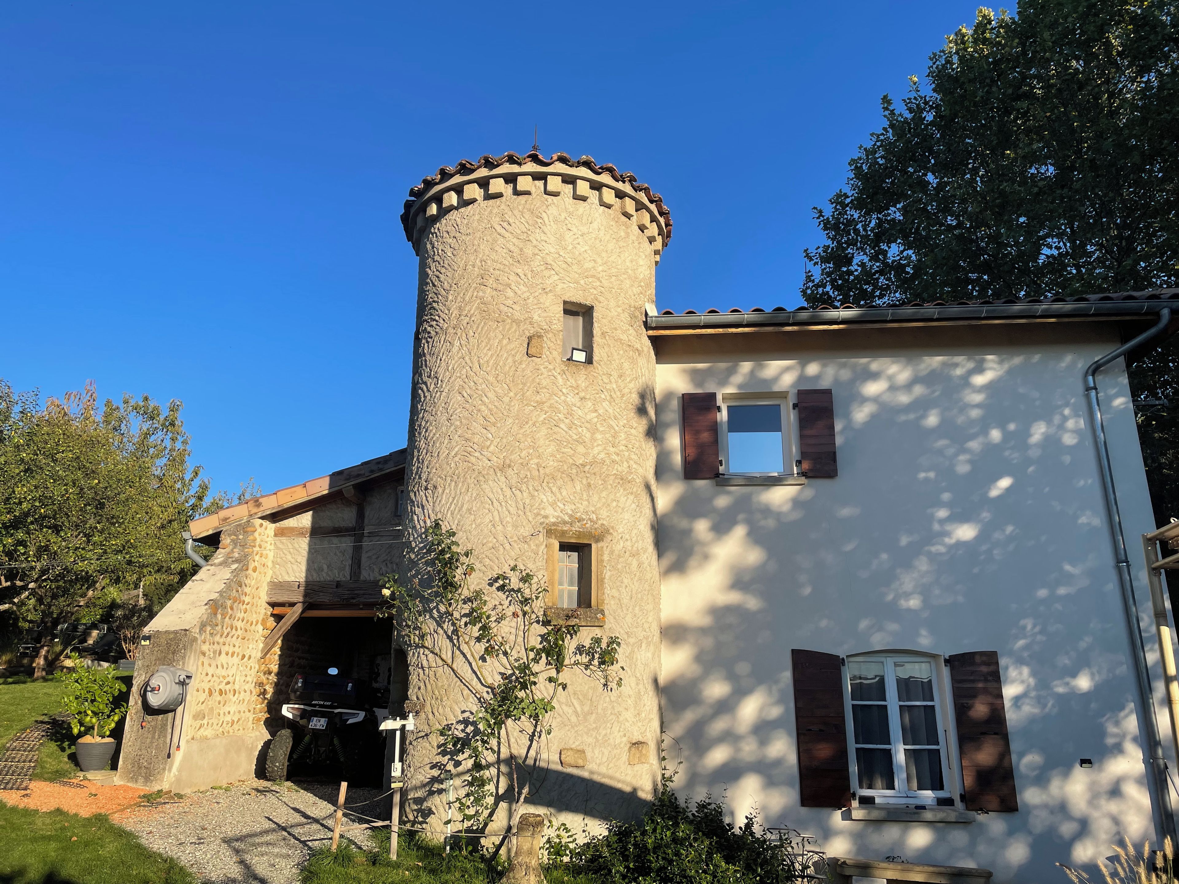 Una torre de piedra adosada a un edificio, con una pequeña ventana y una puerta.
