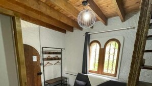 Une pièce avec un plafond en bois, un canapé, une petite table, un porte-manteau suspendu et une fenêtre donnant sur un beau paysage.