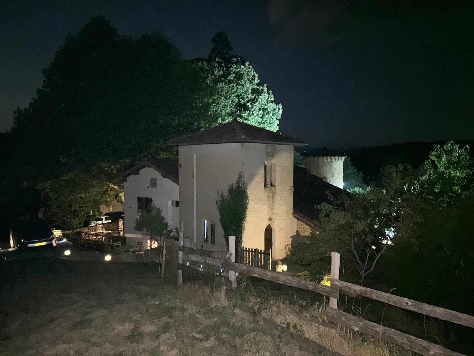 Un edificio blanco con una torre, rodeado de árboles y una valla de madera.