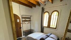 Une chambre à coucher avec un lit, un plafond en bois, une fenêtre et une porte.