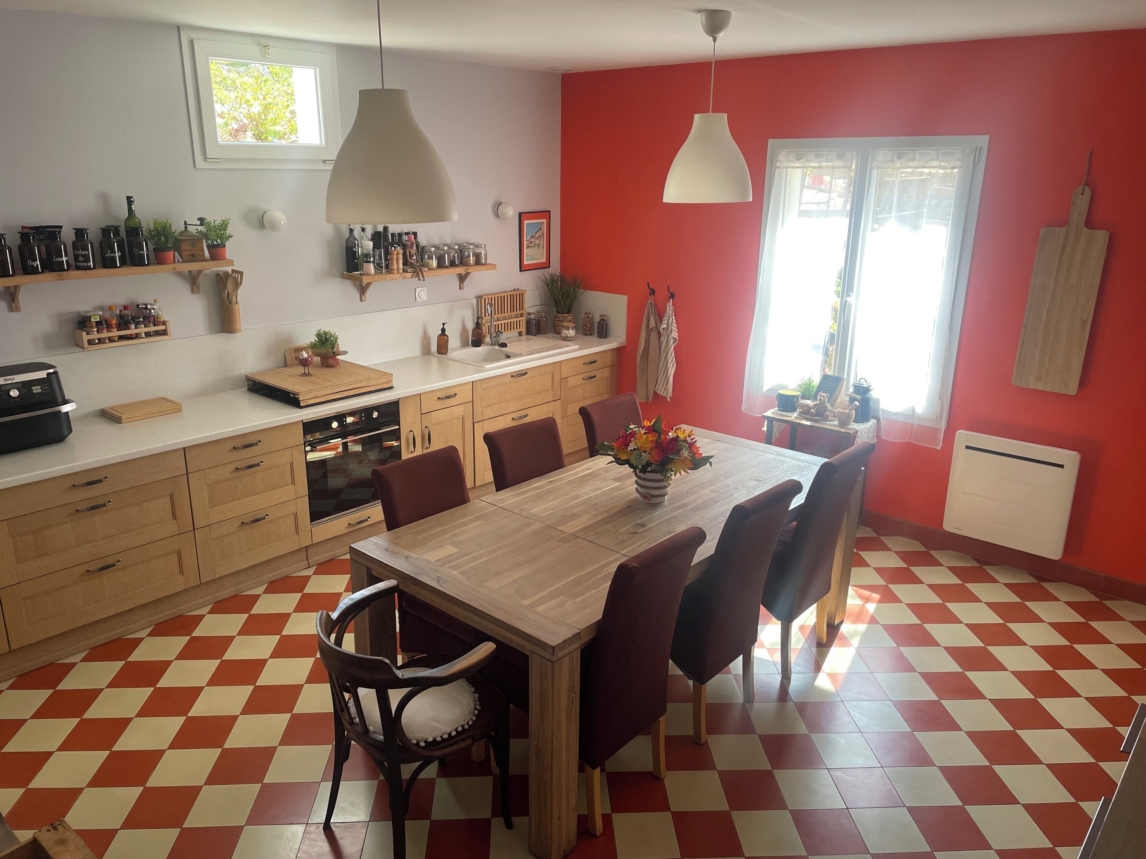 Une cuisine avec un carrelage à motifs, des meubles en bois, un îlot central et une table à manger avec des chaises.