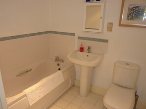 Et badeværelse med badekar, vask og toilet.