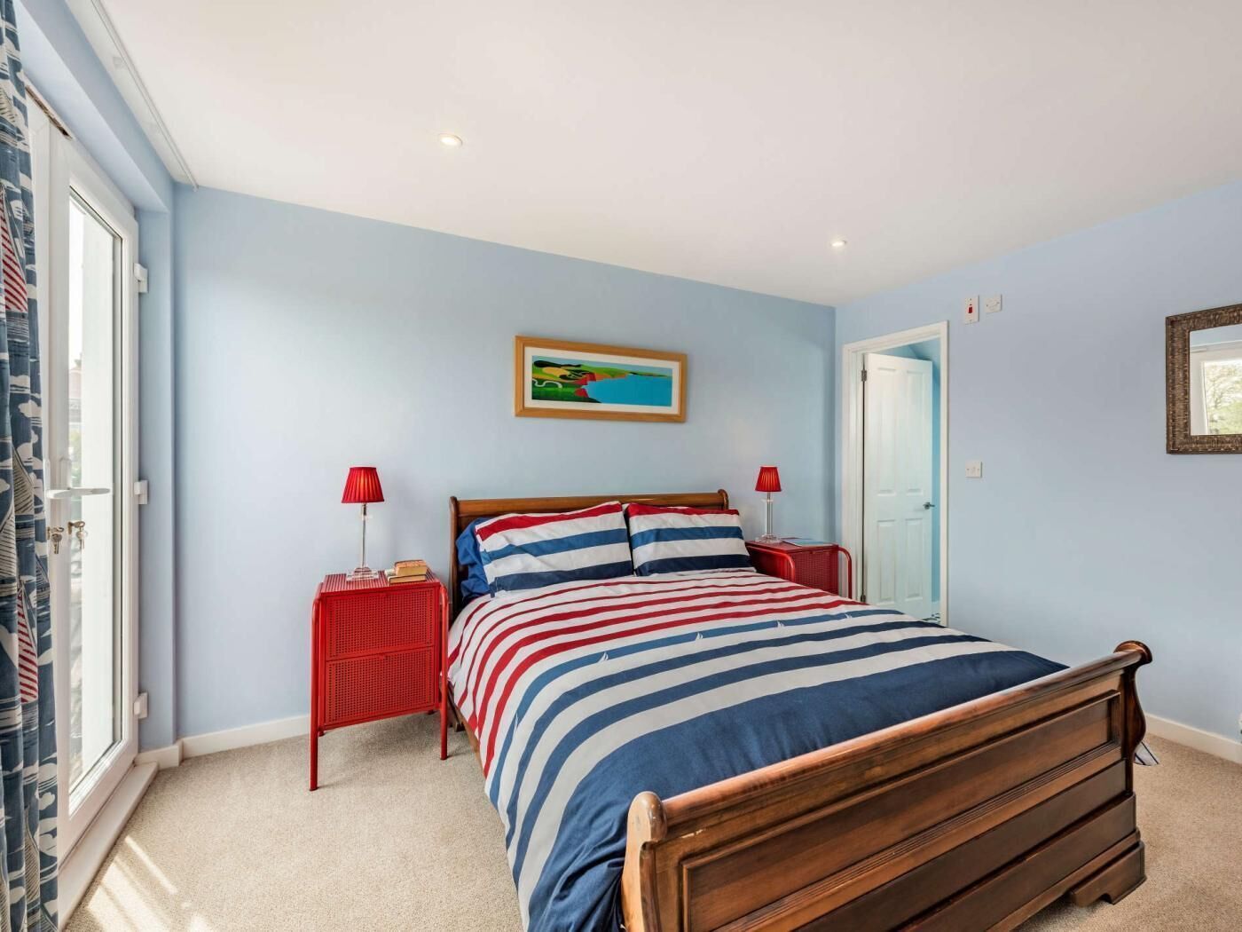 Une chambre à coucher avec un lit, deux tables de chevet, une fenêtre avec des rideaux et une porte.