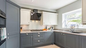 Una cocina moderna con armarios grises, estufa a gas y ventana con vista a follaje.