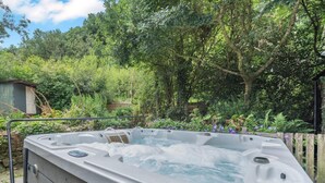 A hot tub in a garden with trees and a shed in the background. - 3 Bed in Lampeter (oc-55308) (Ciliau Aeron)