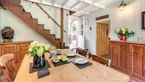 A dining area with a wooden table set for two, a staircase, and a view of the outdoors. - 3 Bed in Lampeter (oc-55308) (Ciliau Aeron)