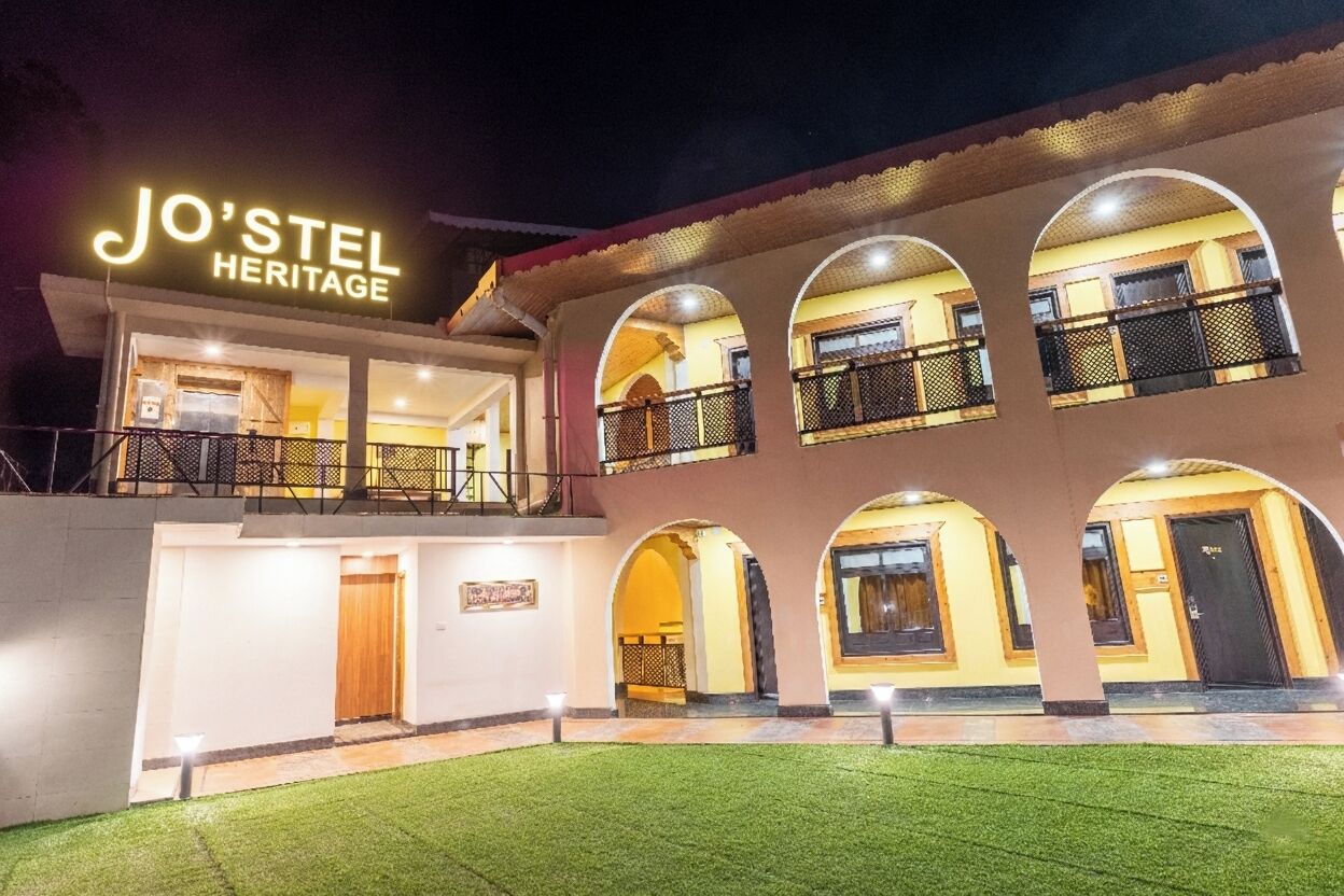 Um hotel com uma placa que diz 'JO'STEL HERITAGE', apresentando um pátio com várias arcos e sacadas.