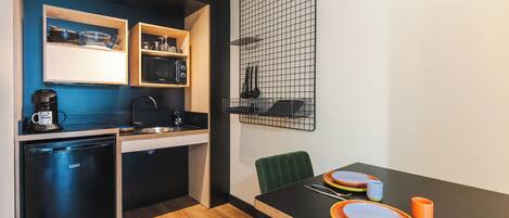 A compact kitchen with a dishwasher, microwave, and a small dining area with a table set for two.