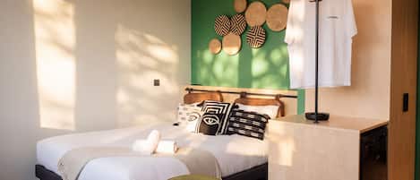 Una habitación de hotel moderna con cama, mesita de noche y un pequeño rincón de descanso.
