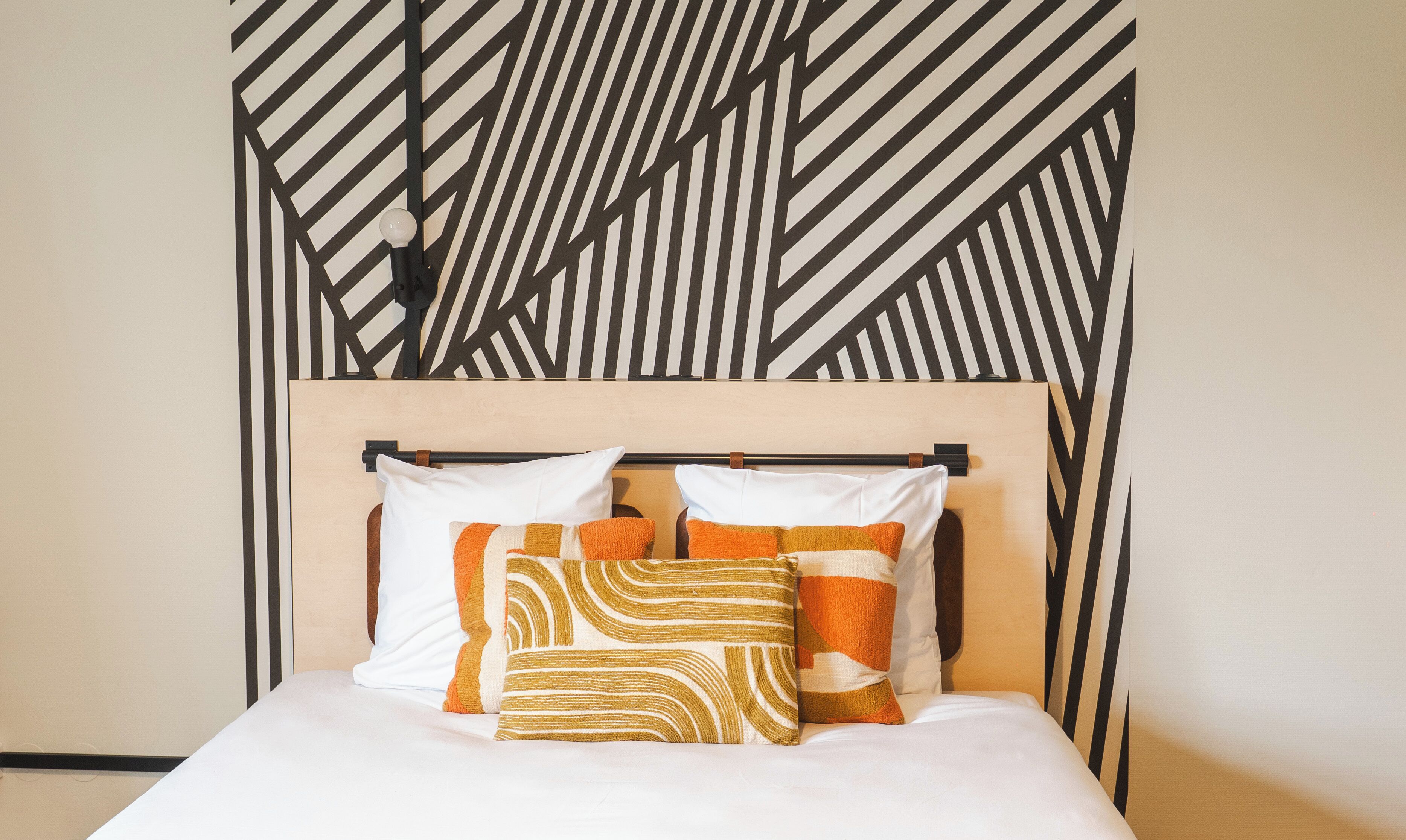 A bed with a wooden headboard, two white pillows, and two patterned pillows.