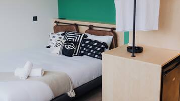 A modern hotel room with a bed, a bedside table, a chair, a wardrobe, and a wall with decorative plates.