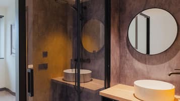 A modern bathroom with a glass-enclosed shower, a round mirror, and a wooden vanity with a sink.