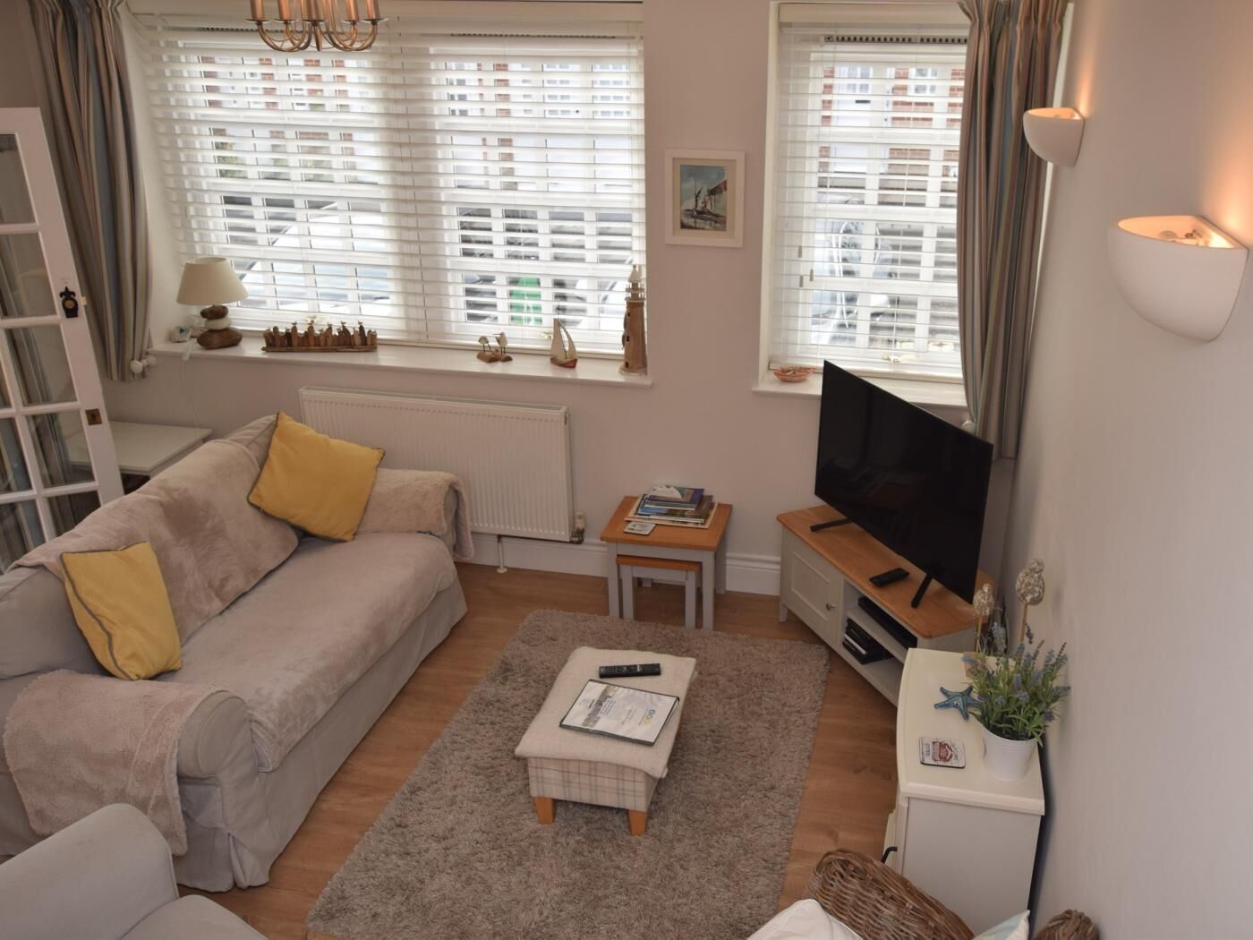 Ein Wohnzimmer mit einer Couch, einem Couchtisch, einem Fernseher und einem kleinen Tisch mit Büchern.